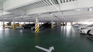 A multi-level parking garage with cars parked in designated spaces, marked with directional arrows on the floor. - Suncheon Noblesse Hotel (Suncheon)