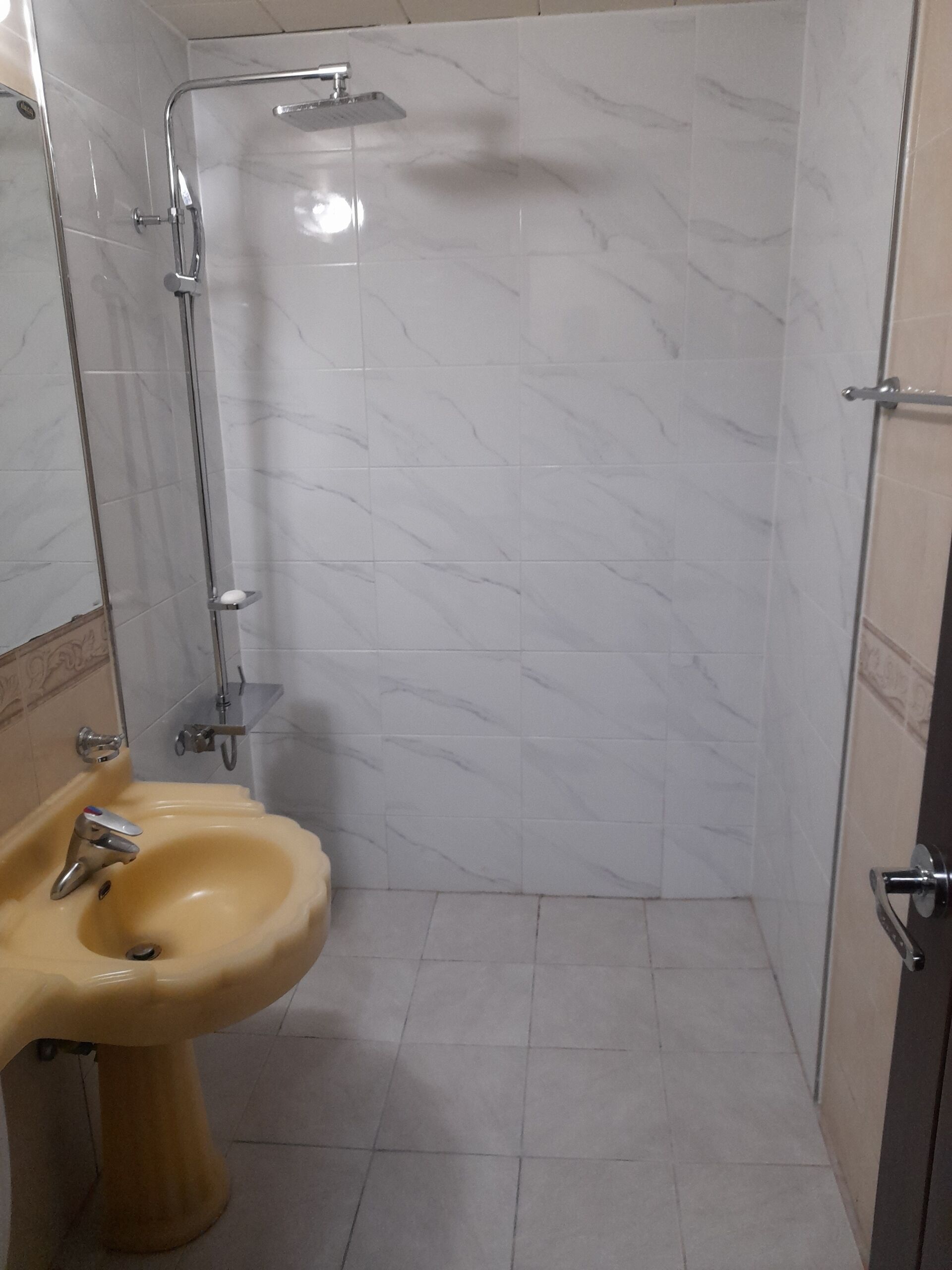 Un bagno con doccia, lavandino e pareti piastrellate.