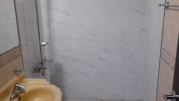 Un bagno con doccia, lavandino e pareti piastrellate.