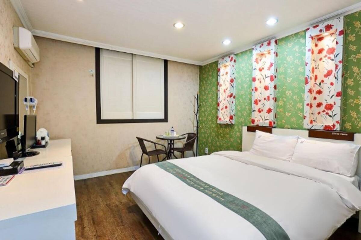 A hotel room with a bed, desk, chair, and a television.
