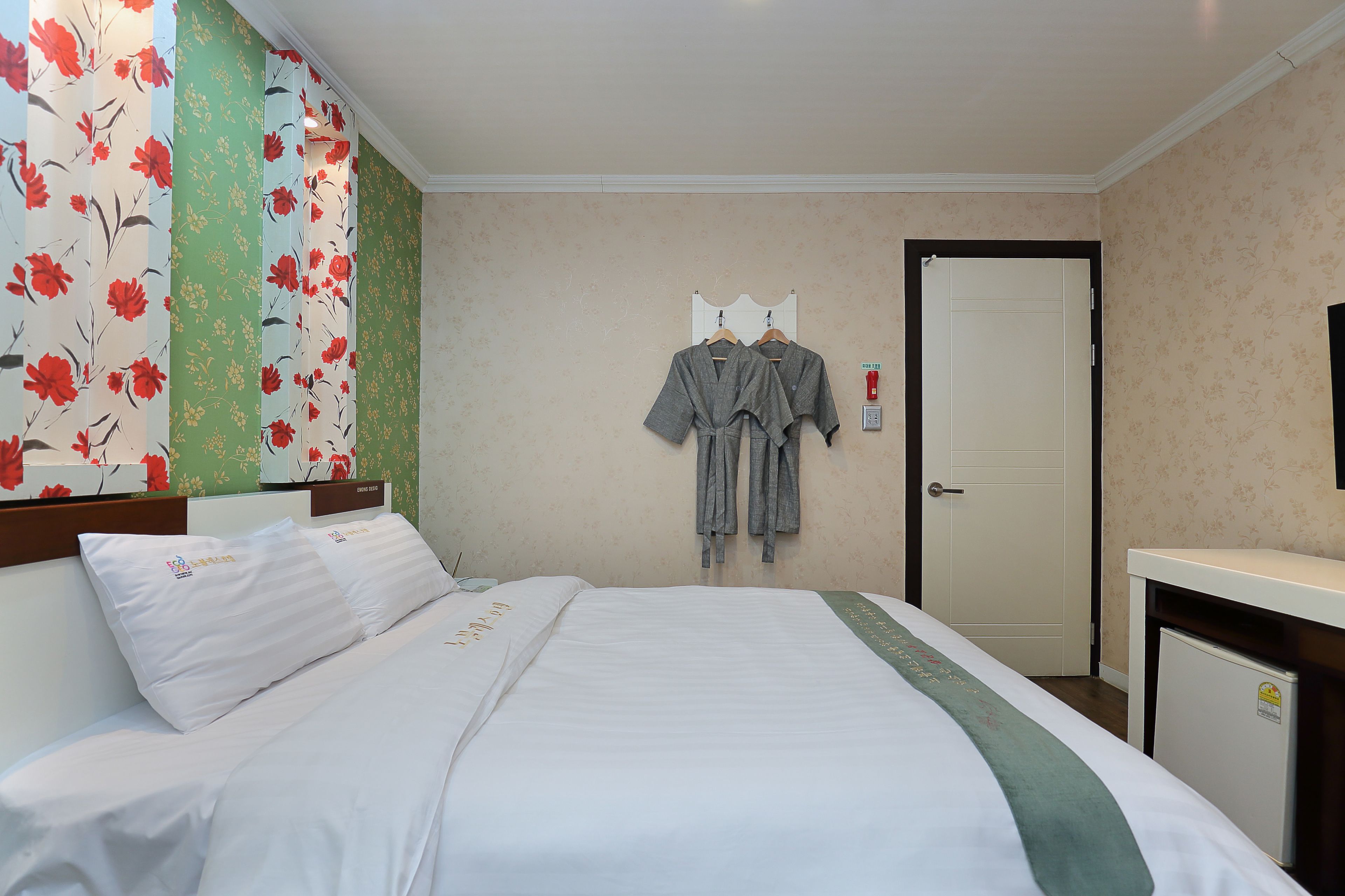 A hotel room with a bed, a desk, and a wardrobe.