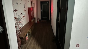 En smal gang med trægulv, en bænk og en dør for enden.