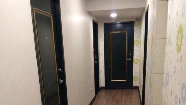 A narrow hallway with wooden flooring and two dark doors with gold accents. - Come Inn Taipei 3 (Taipei)
