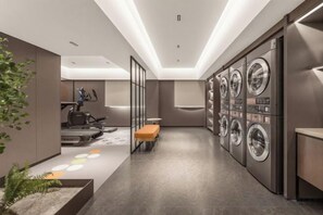 A modern laundry facility with multiple washing machines, a bench, and exercise equipment.