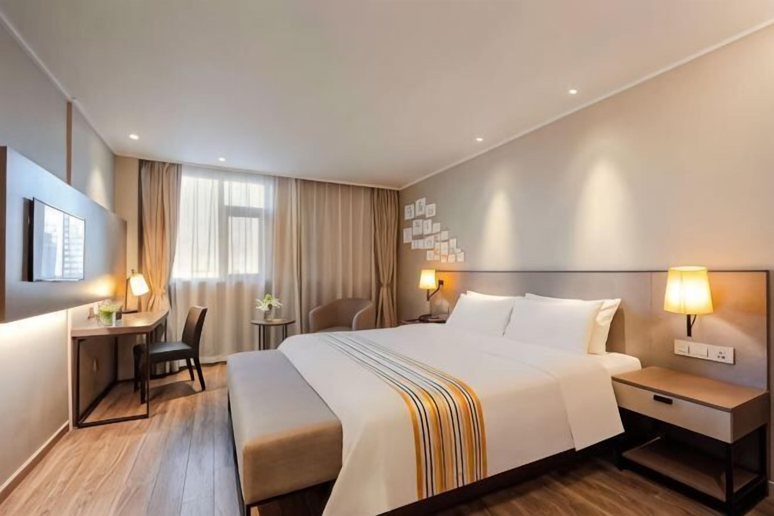 A hotel room with a large bed, bedside tables, a desk, and a chair.