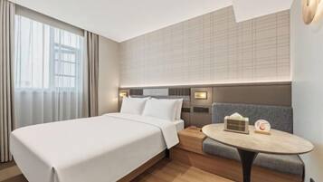 A hotel room with a large bed, a small table, and a seating area.