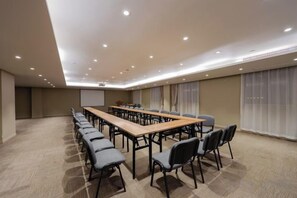A conference room with a long table and chairs, a projector screen, and a carpeted floor.