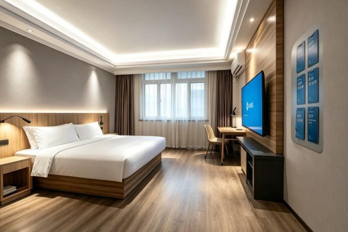 Una habitación de hotel moderna con una cama grande, un escritorio y un televisor de pantalla plana.