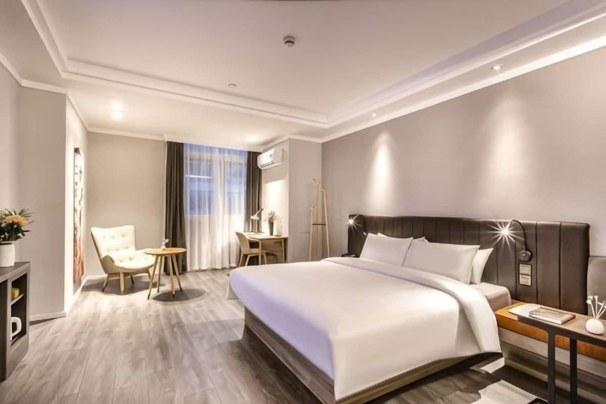 Une chambre d’hôtel moderne, dotée d’un grand lit, d’un bureau, d’une chaise et d’une petite table.