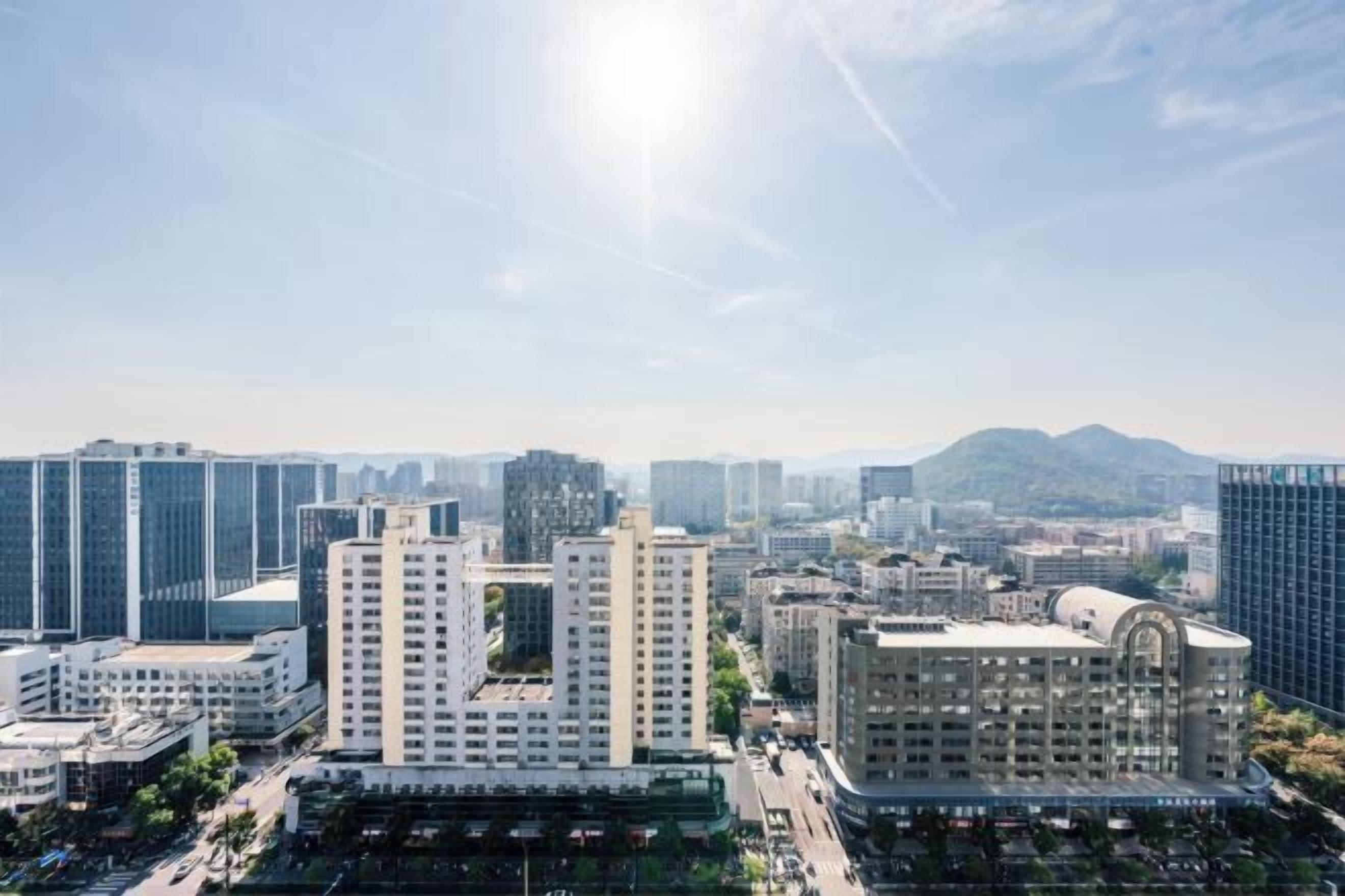 A cityscape with modern high-rise buildings, a prominent curved building, and a mountain in the background.