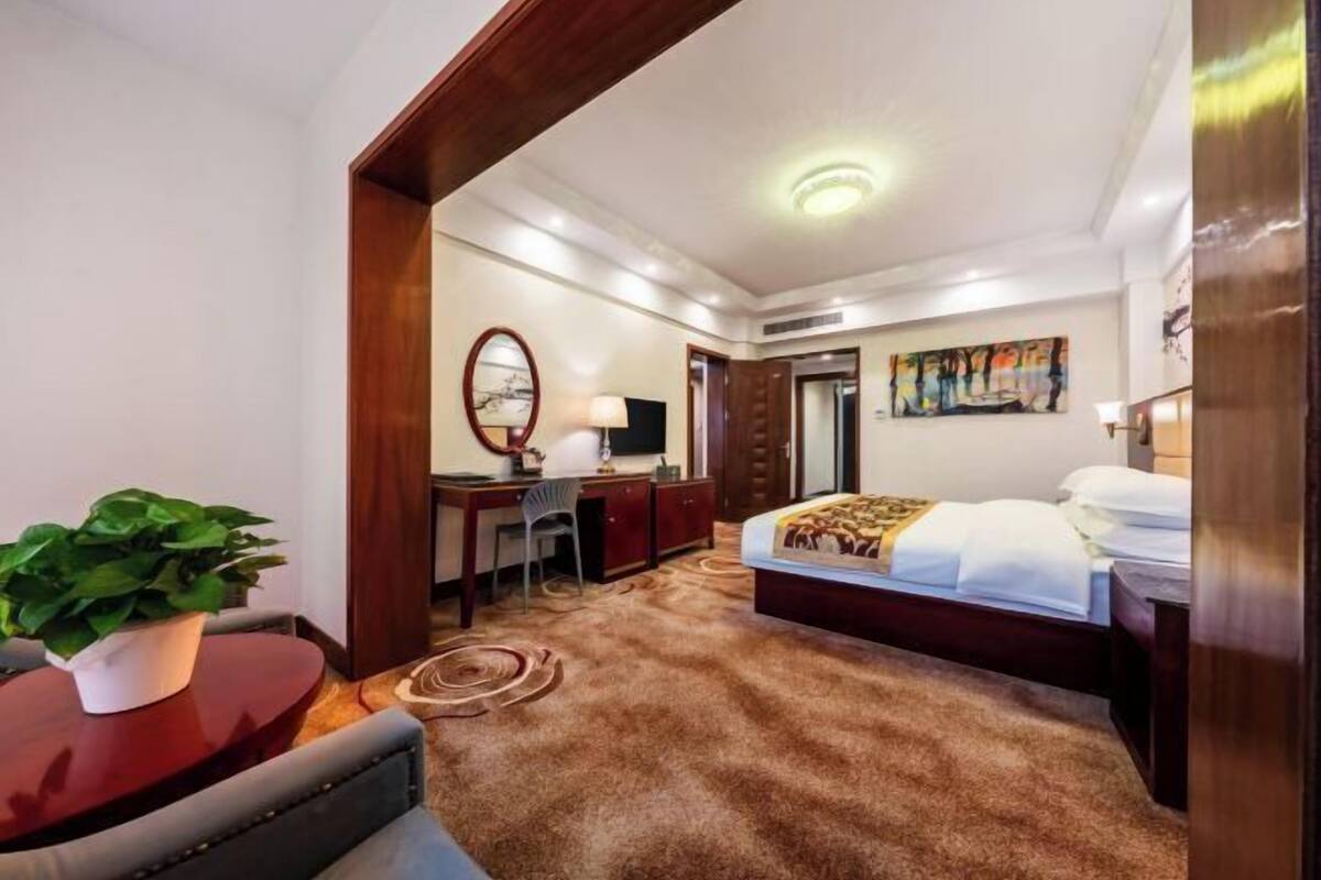 Una habitación de hotel con cama, escritorio, silla y una planta en maceta.