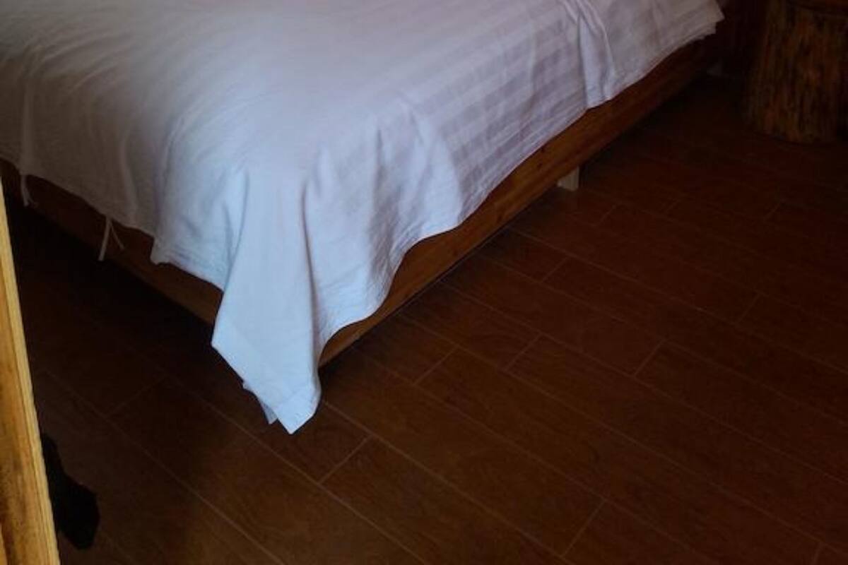 Una cama doble con cabecera de madera en una habitación con suelo de baldosas.