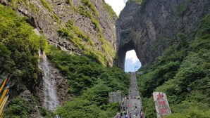 A stone staircase leading up to a natural rock arch formation surrounded by lush greenery. - Zhang Jiajie Longquan Inn (Zhangjiajie)