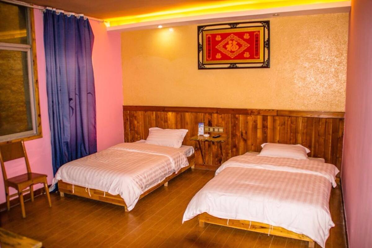 Una habitación con dos camas de madera, cabeceros de madera, una mesita con una lámpara y un cuadro en la pared.