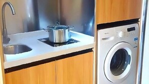 A kitchen with a stainless steel sink, a pot on the counter, and a front-loading washing machine. - Guangzhou TianHe Hotel (Panyu Shiqiao Subway Station) (Guangzhou)
