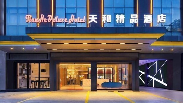 The exterior of Tianhe Deluxe Hotel with a modern facade, large glass windows, and illuminated signage. - Guangzhou TianHe Hotel (Panyu Shiqiao Subway Station) (Guangzhou)