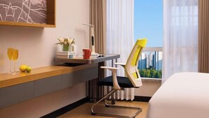 A hotel room with a bed, a desk with a chair, a window with a city view, and a small table with a vase and a red cup. - Guangzhou TianHe Hotel (Panyu Shiqiao Subway Station) (Guangzhou)
