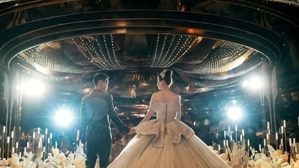 A couple walking through a grand hall with a chandelier and floral arrangements. - Huaxi Hotel Dujiangyan (Chengdu)