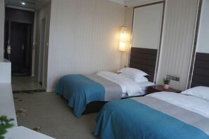 A hotel room with two beds, a bedside table with a lamp, and a mirror. - Huaxi Hotel Dujiangyan (Chengdu)