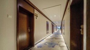 A hotel corridor with wooden doors, a patterned carpet, and a ceiling with recessed lighting. - Huaxi Hotel Dujiangyan (Chengdu)