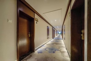 A hotel corridor with wooden doors, a patterned carpet, and a ceiling with recessed lighting. - Huaxi Hotel Dujiangyan (Chengdu)