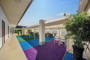 A covered outdoor area with a blue carpet, seating, and potted plants. - Huaxi Hotel Dujiangyan (Chengdu)