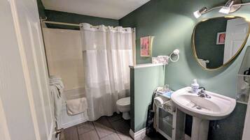Een badkamer met een douche, toilet, wastafel en een spiegel.