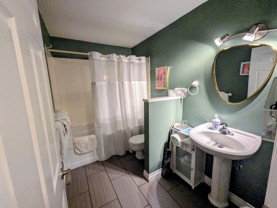 Een badkamer met een douche, toilet, wastafel en een spiegel.