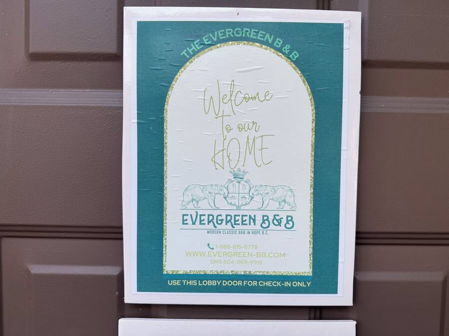 Letrero de bienvenida para Evergreen B&B, con un emblema de oso e información de contacto.