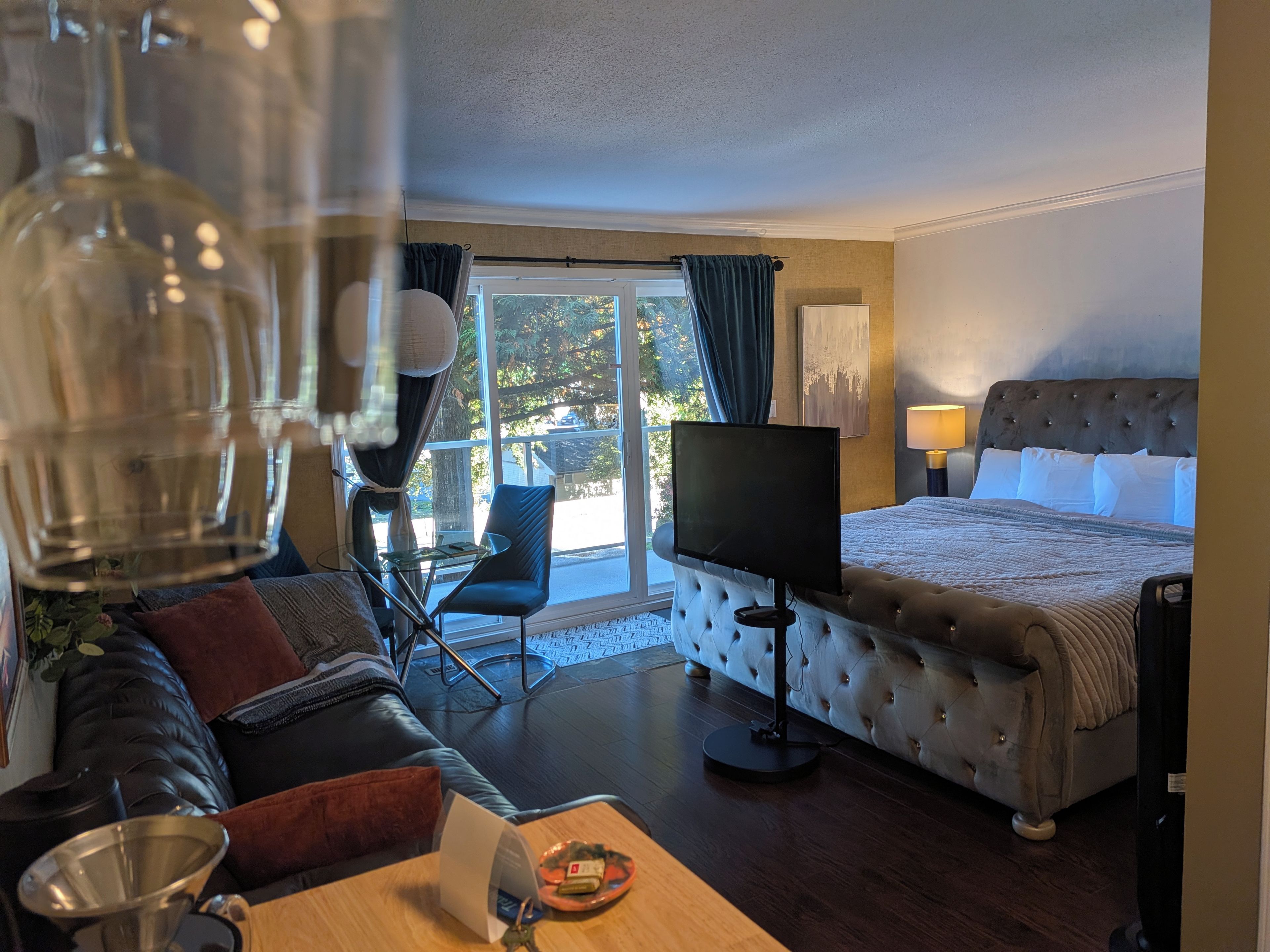 A hotel room with a bed, a television, a sofa, a coffee table, and a view of the outdoors.