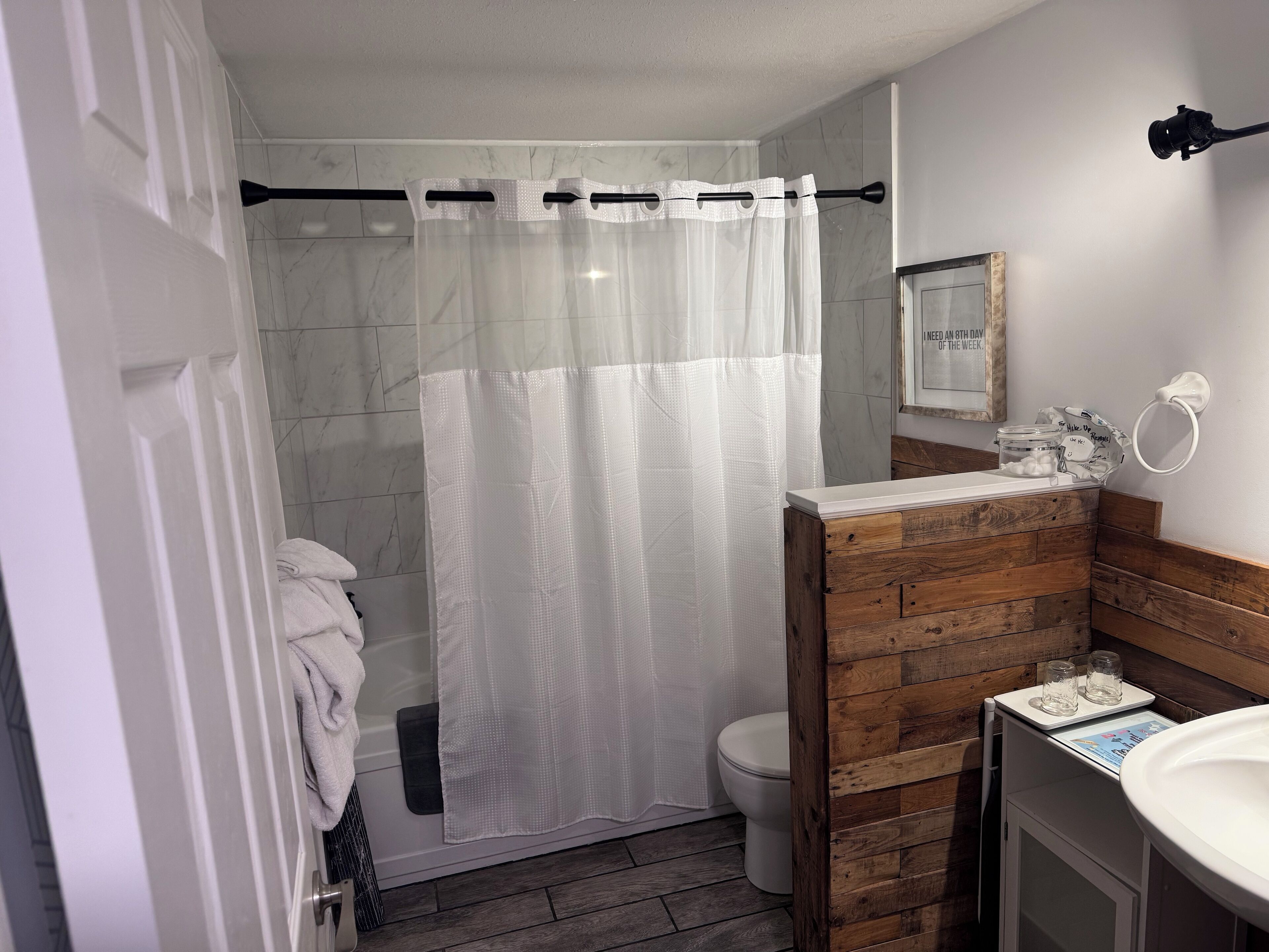 Un baño con cortina de ducha, inodoro, lavabo y tocador de madera.