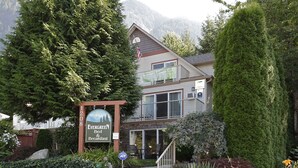 Um edifício de dois andares com uma placa que diz "Evergreen Bed & Breakfast" e vista para montanhas ao fundo.