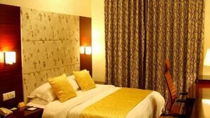 A hotel room with a large bed, two bedside lamps, a patterned headboard, and a curtain with a geometric design. - Jing Lin (Beijing)