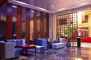 A modern lobby with seating areas, a reception desk, and a large window with a view. - Jing Lin (Beijing)