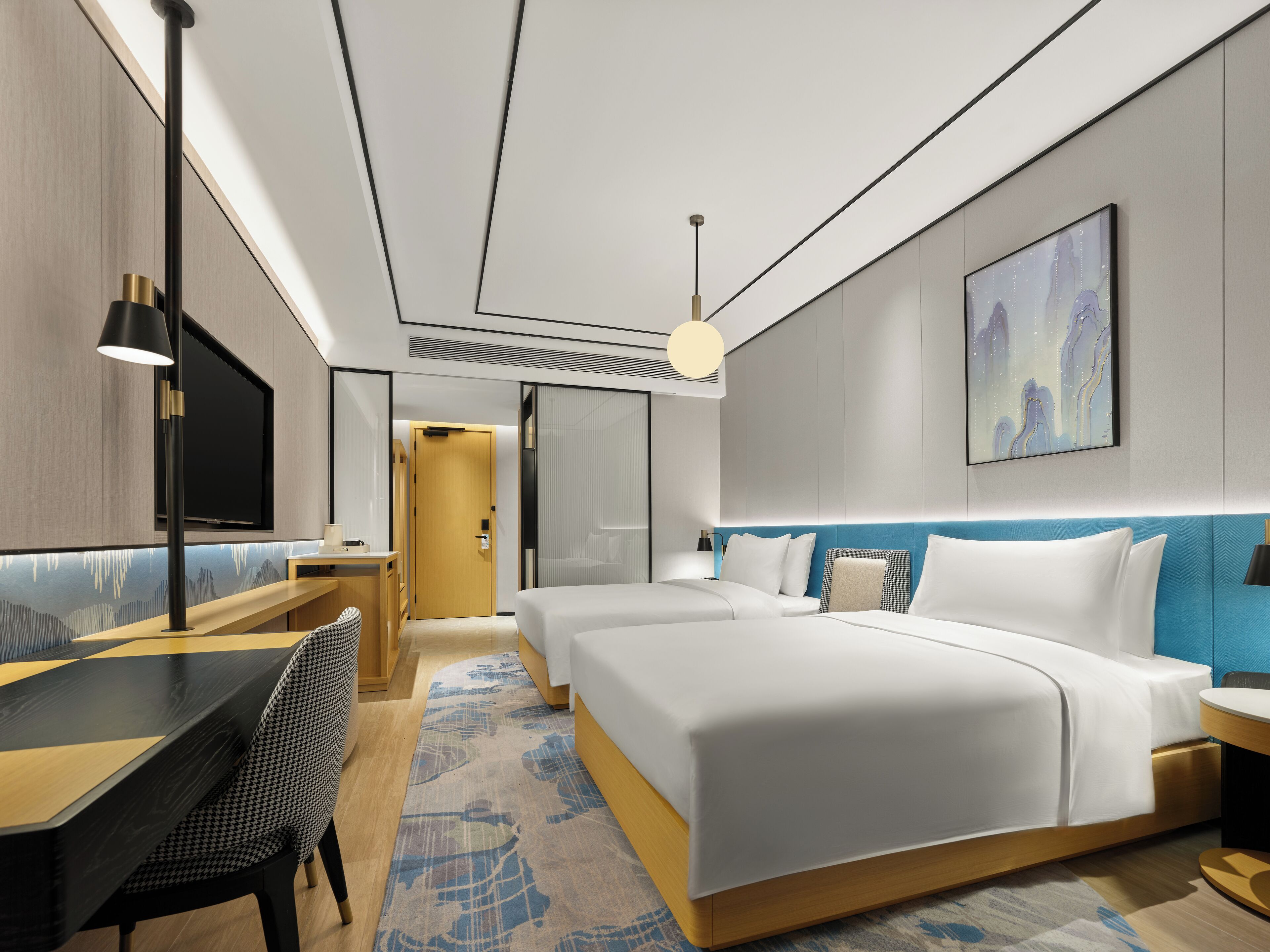 Ein modernes Hotelzimmer mit einem großen Bett, einem Schreibtisch und einem Fernseher.
