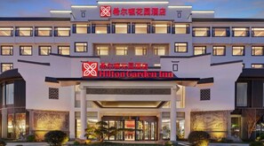 Un hôtel à plusieurs étages, reconnaissable à son grand panneau « Hilton Garden Inn ».
