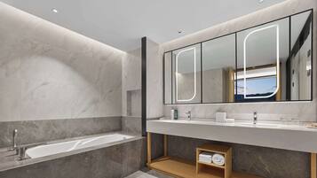 A modern bathroom with a large mirror, a bathtub, and a vanity with a wooden shelf.