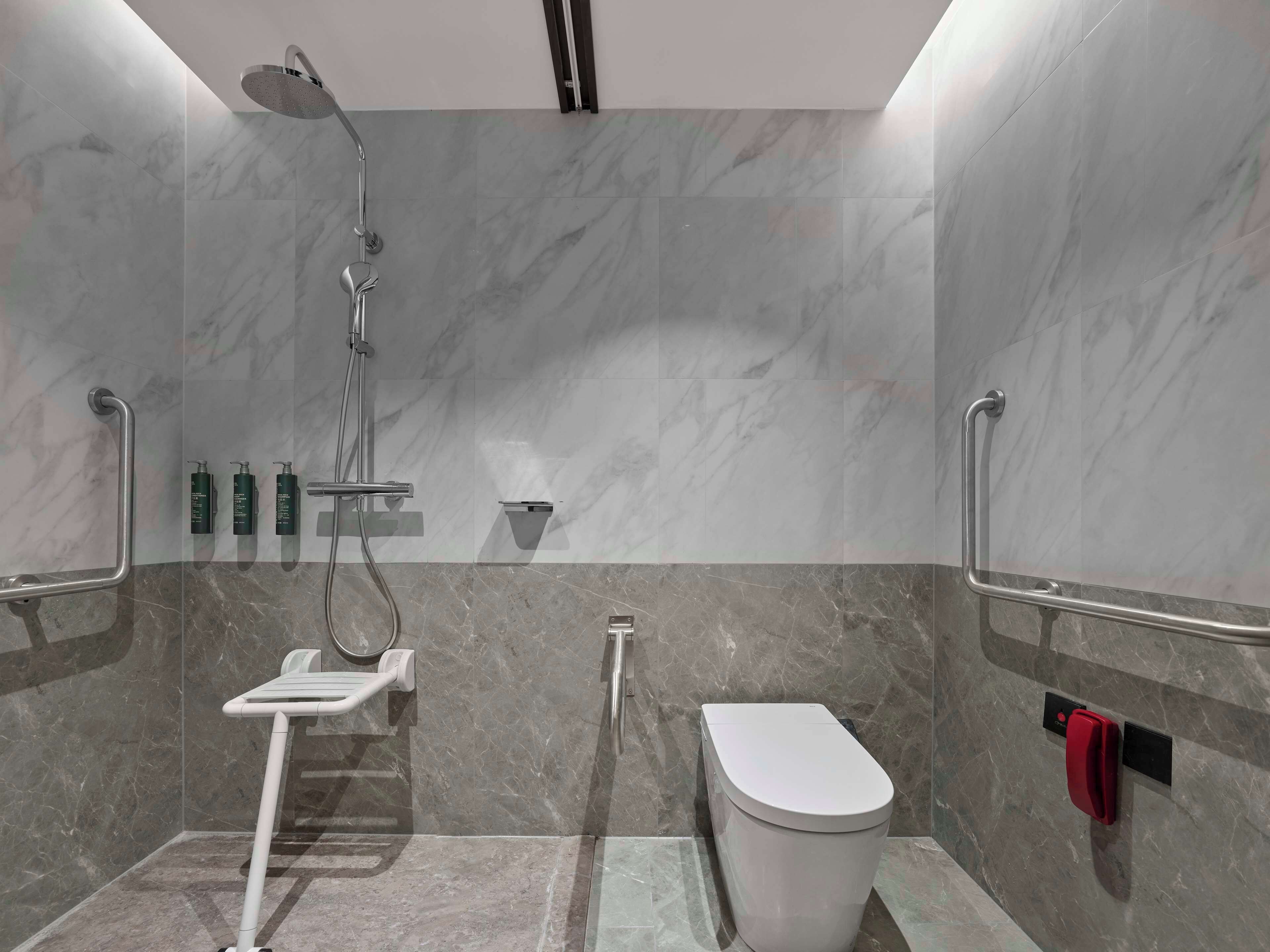 Un baño moderno con ducha, inodoro y barras de apoyo.