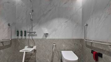Un baño moderno con ducha, inodoro y barras de apoyo.