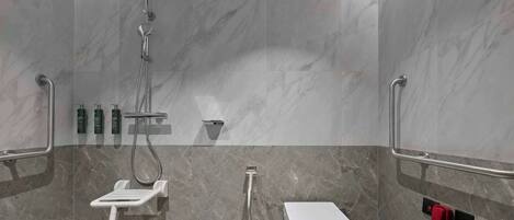 Une salle de bain moderne équipée d’une douche, de toilettes et de barres d’appui.