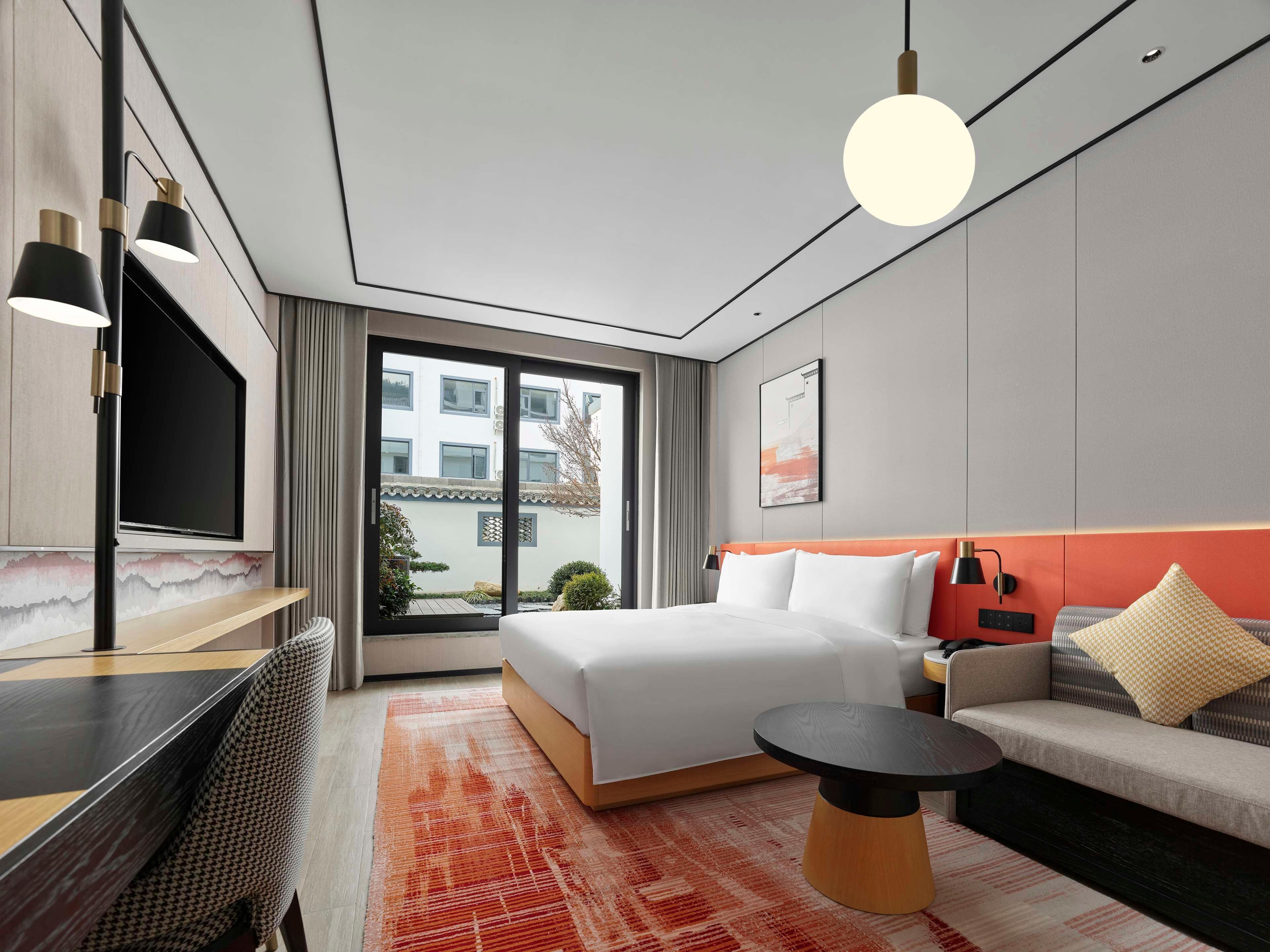 Une chambre d’hôtel moderne équipée d’un lit, d’un canapé, d’un bureau et d’une grande fenêtre.