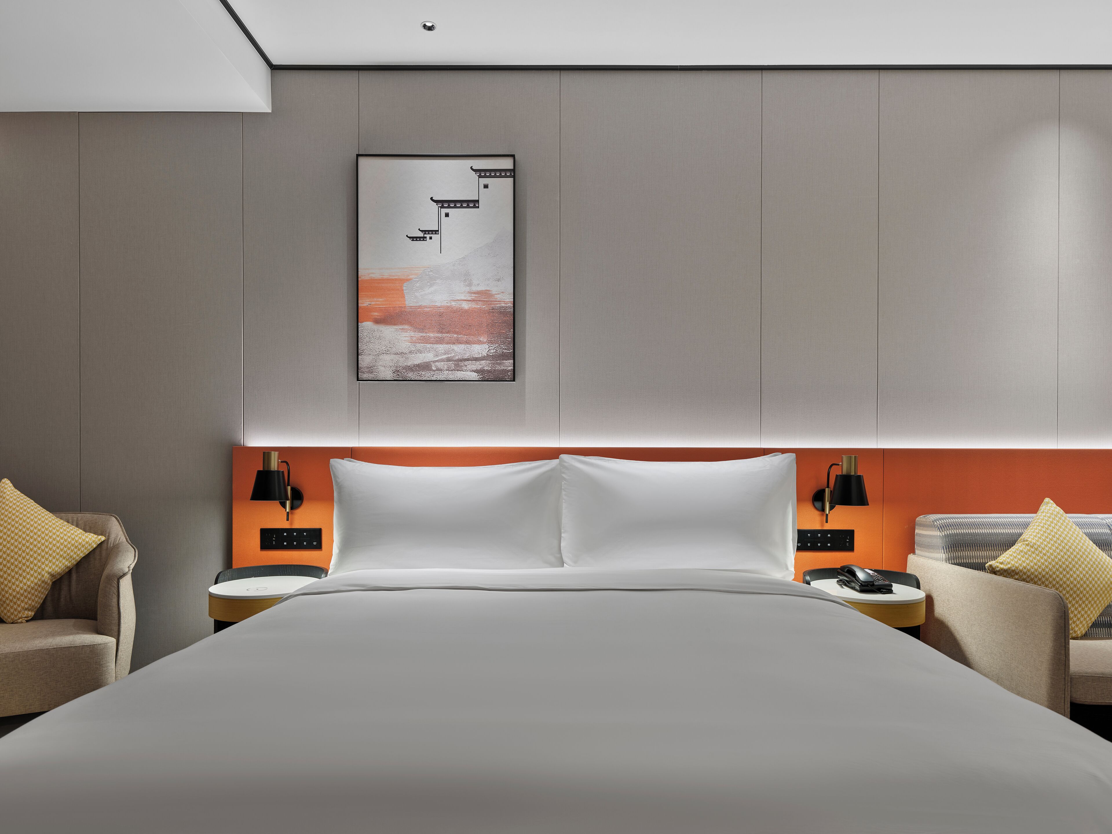 Ein modernes Hotelzimmer mit einem großen Bett, zwei Nachttischen und einem an der Wand befestigten Kunstwerk.