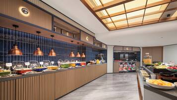 Un buffet moderne, proposant une grande variété de plats, avec un comptoir en bois et un éclairage suspendu.