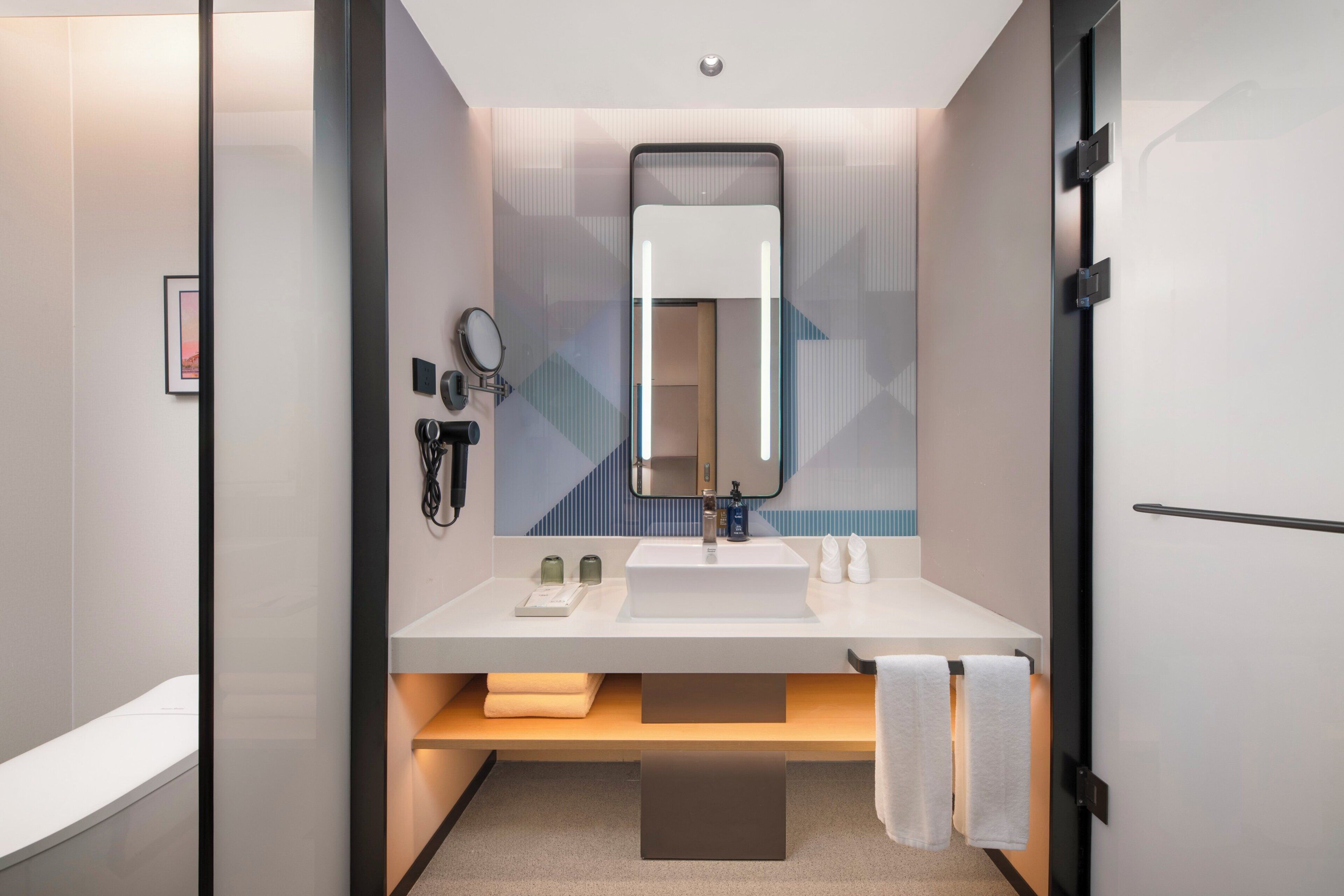 A modern bathroom with a white vanity, a mirror, a towel rack, and a sink.