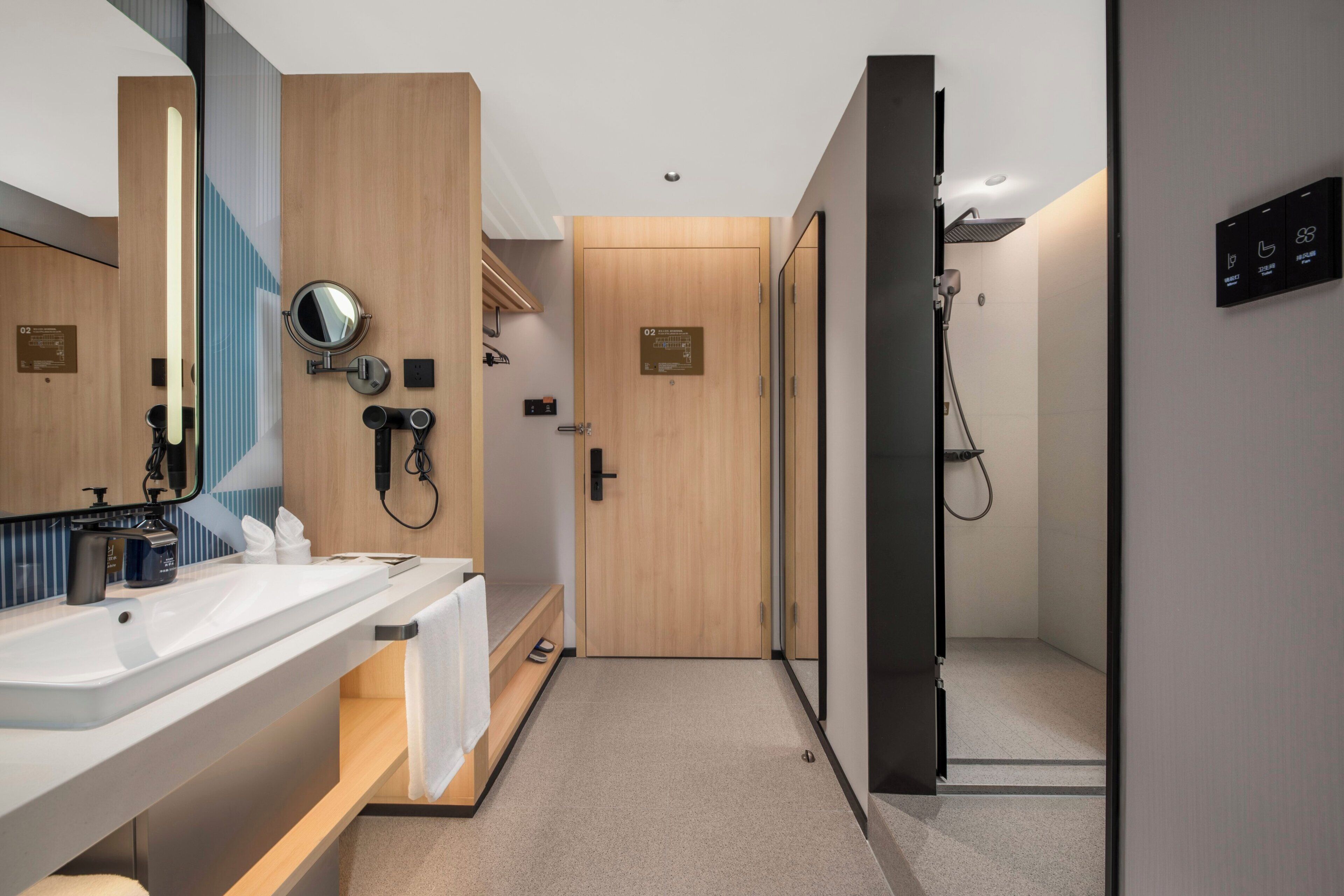 A modern bathroom with a sink, mirror, towel rack, and shower area.