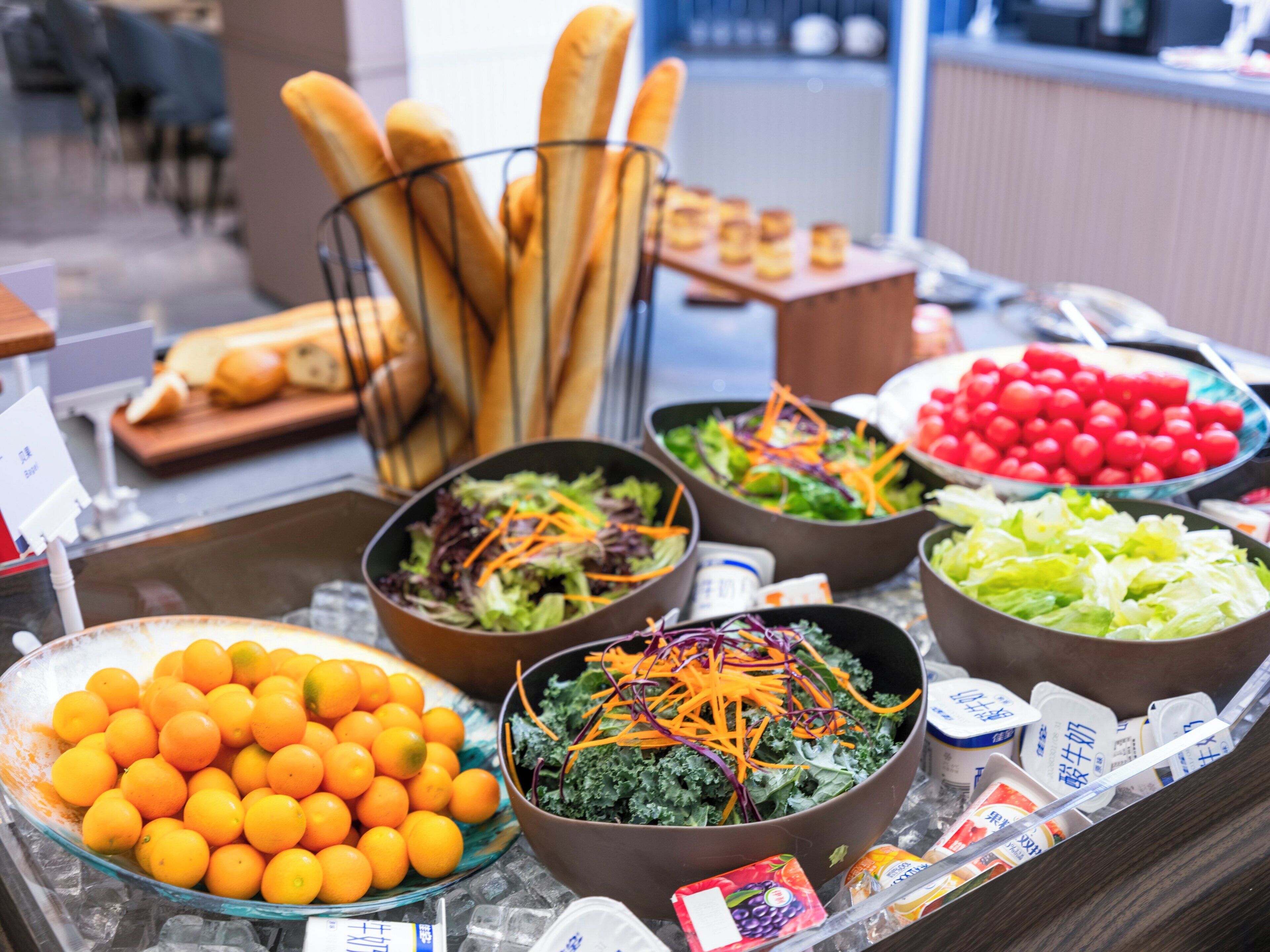 A buffet with various food items including salads, fruits, and bread.