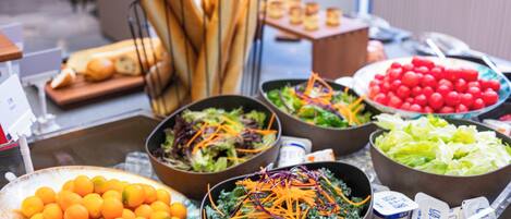 Ein reichhaltiges Buffet mit verschiedenen Speisen, darunter Salate, Früchte und Brot.
