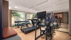 Un gimnasio moderno con cintas de correr, elípticas y pesas libres.