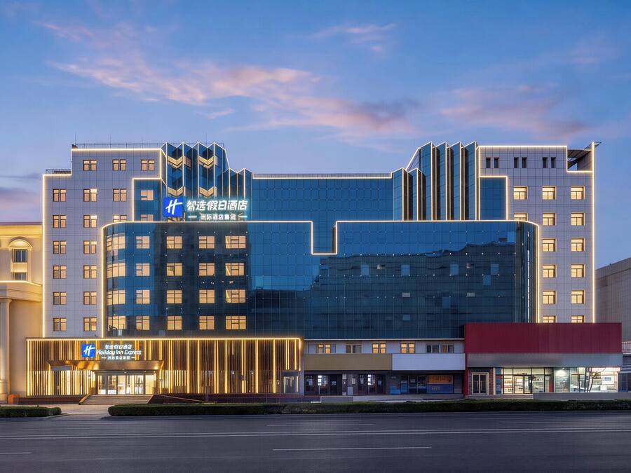 Ein modernes Hotel mit Glasfassade, mehreren Stockwerken und beleuchteter Beschilderung.