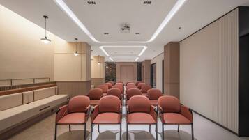 A conference room with rows of chairs, a long table, and a seating area with benches.